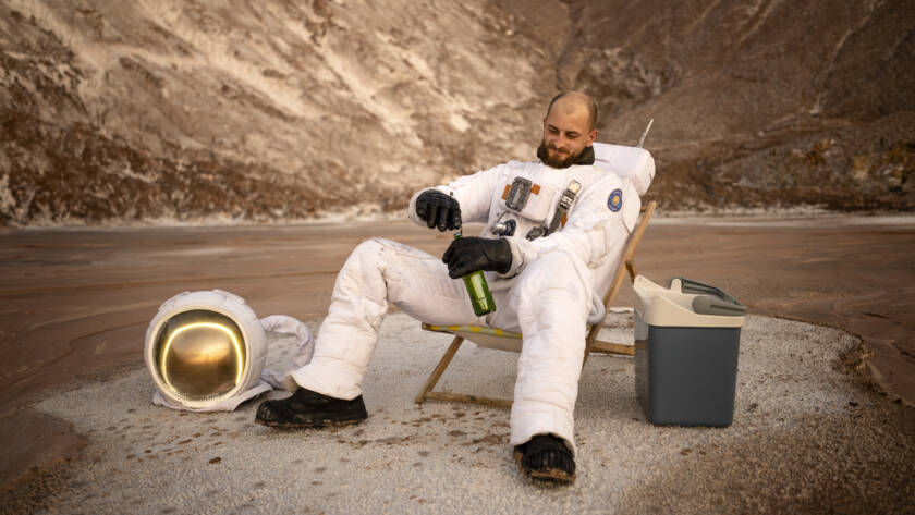 Homem na lua abrindo uma garrafa de cerveja.